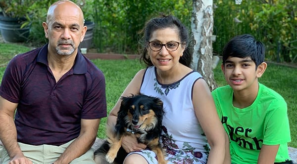Ritu, a former patient of Dr. Jay Granzow, MD, sits outside with her dog, husband, and son.